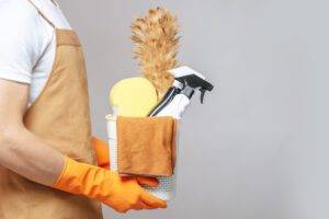 A man in an apron holding a bucket of cleaning supplies.