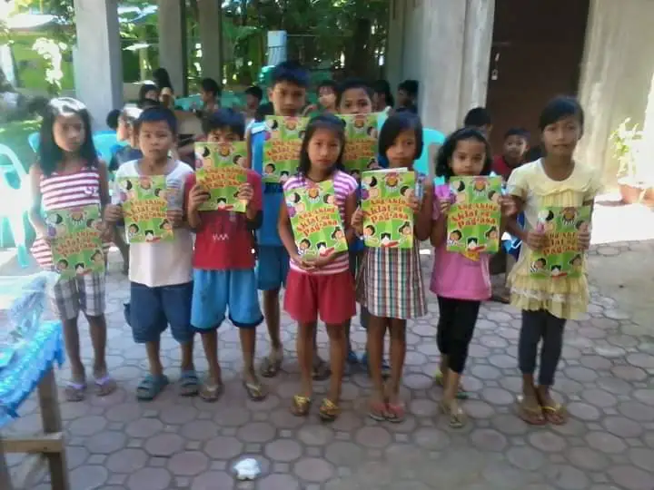 A bunch of kids cheerfully holding signs and have a big smiles on their faces.