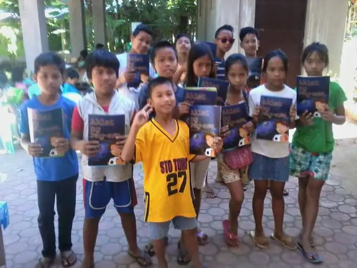 A bunch of kids cheerfully holding signs and have a big smiles on their faces.