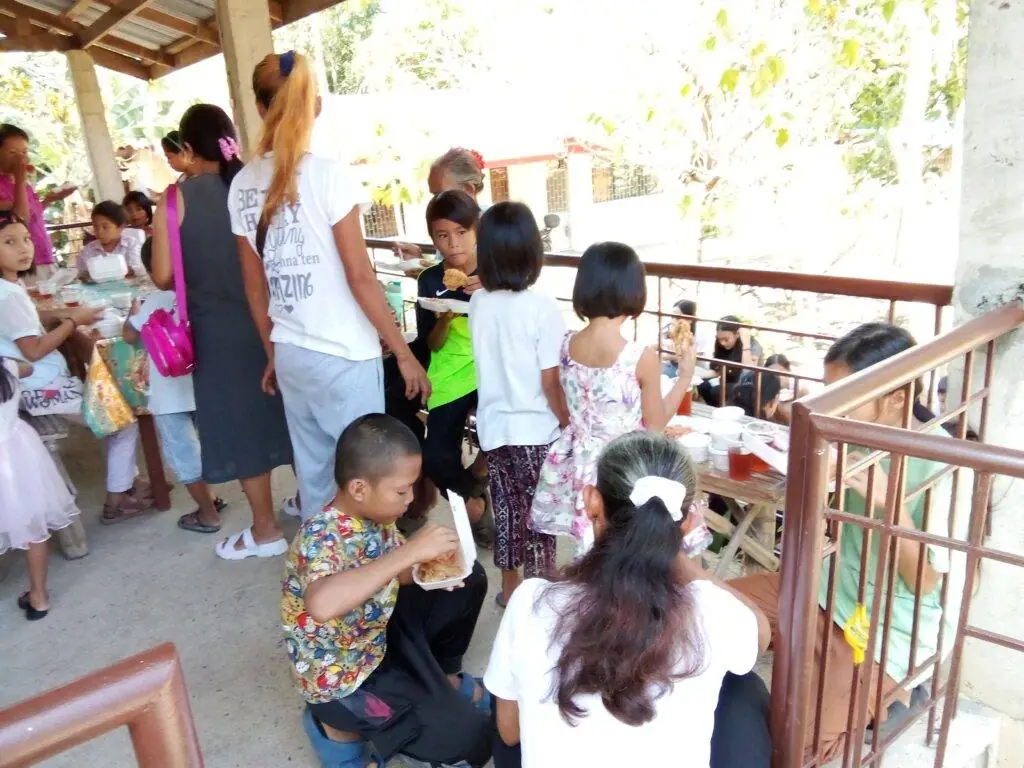 A diverse group of kids and adults sitting around a table, engaged in conversation and activities.